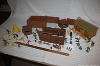 Full lot overview showing assembled fort walls, figurines in various colors, ladders, gate, and other fort accessories arranged for display.