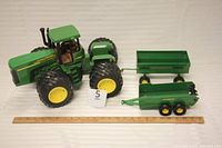 John Deere articulated farm tractor with two wagons and a ruler for size reference.