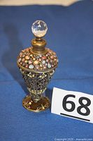 Front view of the decorative perfume bottle showing pewter base and colorful embedded beads.