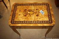 Top-down view showing detailed floral marquetry design with dark floral border on rectangular table top