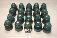 Lot of 20 aqua Hemingray glass electrical insulators grouped together with lot number 128 in front.