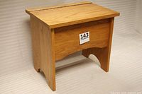 Front and side angle of solid oak stepstool cabinet with wooden grain visible, rectangular shape.