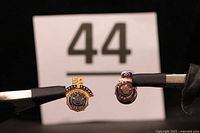 Both American Legion pins held by tweezers showing the 40 Year and 50 Year markings clearly, with a neutral background and lot number 44 behind.