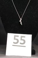 Sterling silver chain laid out on a black display with the cat pendant visible at the center.