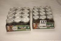 Two sets of Ball Mason jars in original packaging, each set contains 12 jars with metal lids, one set regular mouth, one set wide mouth.