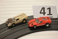 Both slot cars on track showing front quarter view, identifying details and size.