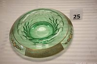 Angled view of the green glass console bowl showing gold floral and cherub designs on rim with green glass raised flower patterns in center.