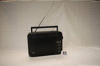 Front view of vintage black General Electric Superadio radio model 7-2887B showing speaker grille, tuning panel, control knobs, and antenna.