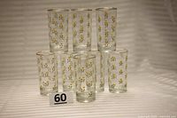 Seven clear glasses arranged in a pyramid shape displaying the yellow rose pattern and gold rims.