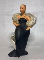 Full view of the figurine standing upright showing the black gown and textured white shawl.