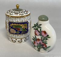 Photo showing front view of the vintage Chinese cloisonné mini lidded box next to the hand-painted porcelain perfume bottle with pink floral design and jade-colored stopper.