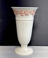 Front view of the Wedgwood Queen's Ware vase showing pink embossed floral decoration on cream background with ribbed body and pedestal base.