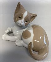 Front and side view of the porcelain cat figurine showing the surprise expression, color pattern, and glossy finish.
