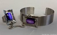 Photo of the bangle and ring showing the rectangular purple insets and chain connecting them