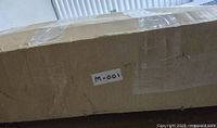 Outer shipping box labeled M-001 containing the desk parts