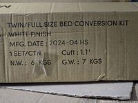 Close-up photo of the shipping box label showing Twin/Full Size Bed Conversion Kit with white finish, manufacturing date 2024-04, weight around 6-7 KGS.