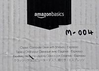 Close-up image of the product labeling on the box showing Amazon Basics brand and desk model name 'Classic Computer Desk with Shelves - Espresso'.