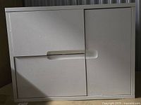 Photo showing the front view of the white bath vanity base cabinet with two recessed handle doors and plain finish.