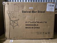 Closed cardboard box with printed image and text indicating a swivel bar stool, model WBBS002BLK, size 21.7"L x 23.4"W x 43.7"H made in China.