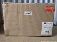 Cardboard box labeled with Golden Lighting brand, model number 1945-1W WHT, and lot number M029.