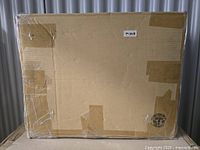 Photo of the packed cardboard box containing the Ayres Lounge Ottoman, sealed with tape, with label M040.