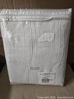 Curtain panel folded and sealed in original packaging showing fabric texture and packaging condition.