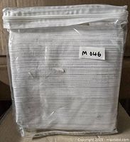 Folded curtain panel inside clear plastic packaging with zipper closure showing item label and fabric texture.