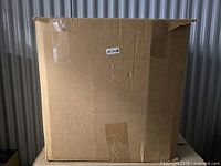 Sealed cardboard shipping box with label and some tape damage.