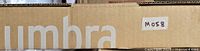 Box showing part of the Umbra logo and lot sticker M058 indicating the product inside.