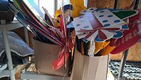 Two large boxes filled with colorful corrugated plastic celebration signs on stakes, including various shapes and designs.