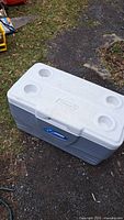 Full view of provided Coleman cooler showing white lid with four molded cup holders and gray body.