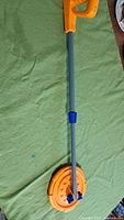 Full view of the orange and gray kids metal detector with a round orange base and blue twist lock on shaft.