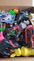 Box containing small toy cars, collectible cards, small figurines, colorful toy pieces, and stuffed Easter bunny