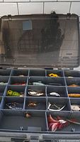 Top view of open Plano fishing tackle box showing compartments with lures and hooks inside.