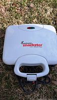 Top view of the closed Toastmaster Snackster sandwich maker showing the white exterior, brand logo, and indicator light.