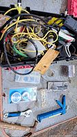 View of assorted tools and hardware items in a container showing cords, ropes, hand tools including pipe wrench, adjustable wrench, caulking gun and hammer.