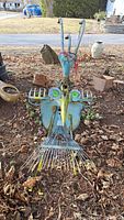 Front view of the bird-shaped metal sculpture made from old rakes and garden tools showing its colors and shapes.