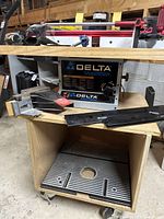 Front view of Delta ShopMaster router table unit on wooden base with accessories scattered