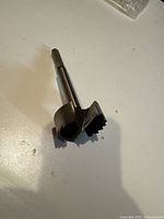 Single Forstner drill bit displayed on a flat surface, showing the cutting edge and shank shape.