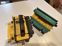 Two yellow Grr-Ripper adjustable push blocks on a white surface showing side and top views, black ergonomic handles, green rubber gripping pads, and adjustment knobs.
