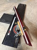 Full view of miter gauge on black slot plate showing aluminum fence, protractor head, brass knobs