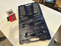 Open Mastercraft blue plastic case showing interior organized for tap and die threading tools, dies arranged in rows with holders and accessories.