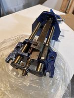 Mastercraft woodworking vise on white surface, showing steel guide rods and screw mechanism along with the adjustable jaws, with plastic wrapping underneath.