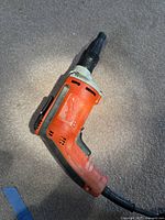 Handheld orange and black Milwaukee power tool showing left side with brand and model markings, minor surface scrapes visible.