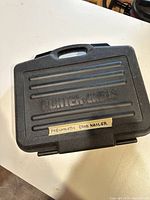 Closed black molded plastic carrying case with Porter-Cable logo and handwritten label 'Pneumatic Brad Nailer'.