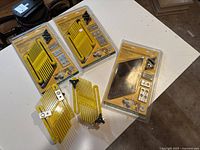 Three yellow Promax featherboards for table saws on a white surface, one packaged double-ended and two unboxed with mounts and knobs