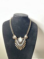 Front overall view of the gold-tone bronze necklace on a black mannequin bust showing chain and pendant details