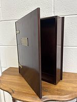 Dark brown wooden storage box opened showing empty interior and hinged lid with brass hinges.