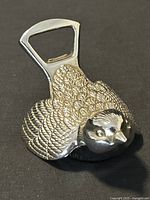 Angled view of silver plated bird bottle opener showing the textured feather details and the bottle opener slot.