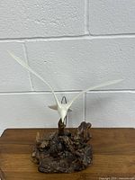 Front view of abstract bird sculpture mounted on wooden base with detailed wood texture and white bird figure in flight position.